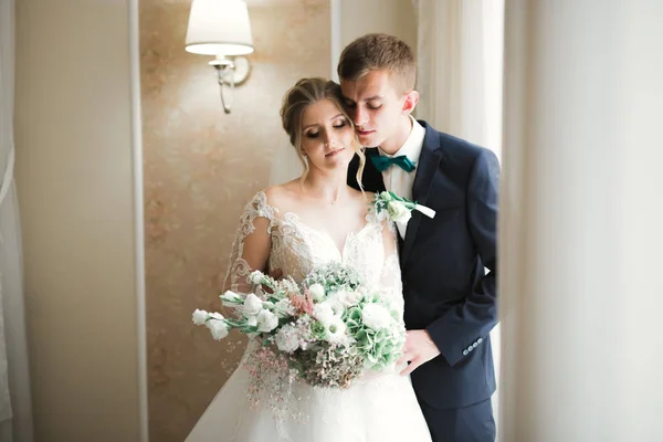 Mooi jong bruidspaar poseren met boeket bloemen in handen — Stockfoto