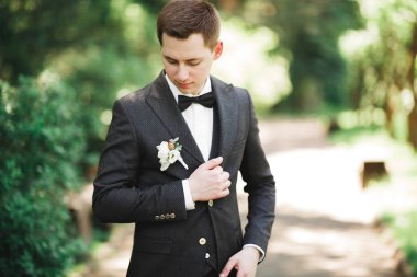 Yaka çiçeğiyle poz veren mutlu yakışıklı damat.