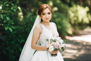 Lüks bir gelin, bir kız buketle poz veriyor ve gülümsüyor.