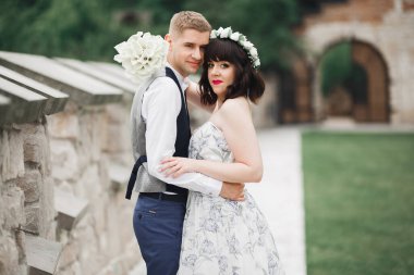 Doğadaki düğün çifti birbirine sarılıyor. Beyaz elbiseli güzel bir kız. Takım elbiseli adam