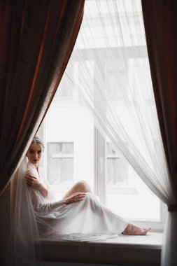 Cüppeli muhteşem gelin bir odada düğün töreni için poz veriyor ve hazırlanıyor.