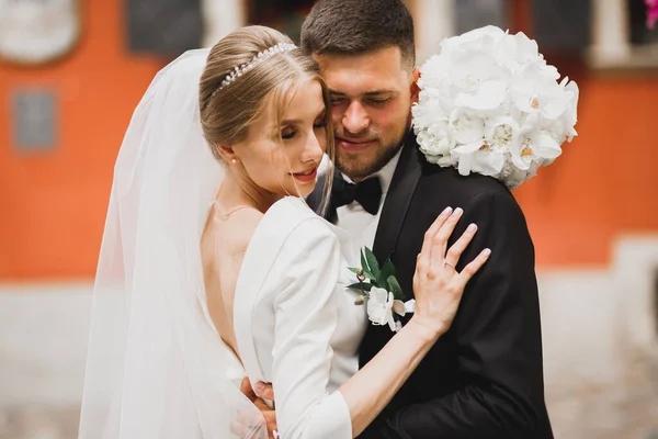 Mooi jong bruidspaar poseren met boeket bloemen in handen — Stockfoto
