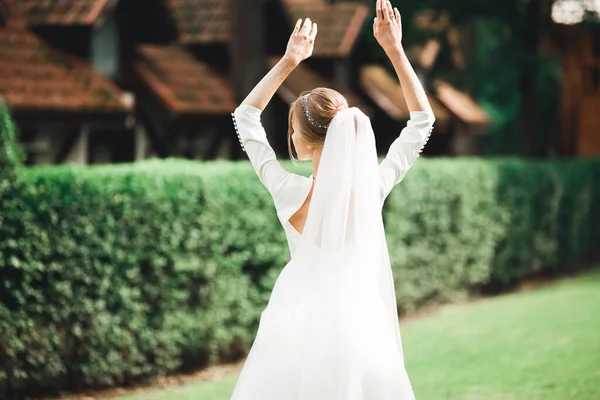 Schöne junge Luxusbraut im Brautkleid posiert im Park — Stockfoto