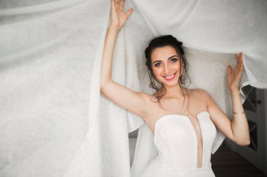 Cüppeli muhteşem gelin bir odada düğün töreni için poz veriyor ve hazırlanıyor.