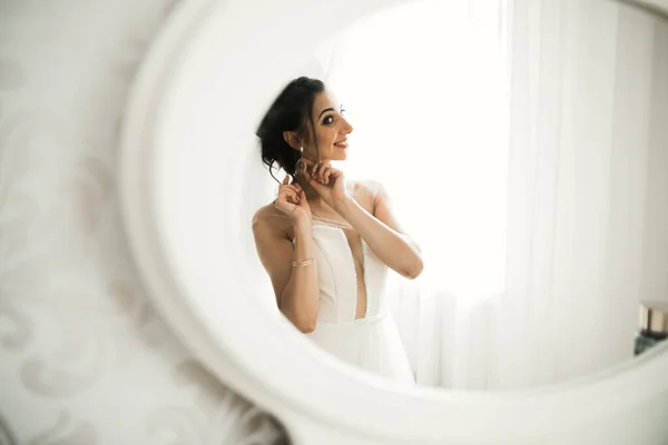 Prachtige bruid in badjas poseren en voor te bereiden op de bruiloft ceremonie gezicht in een kamer — Stockfoto