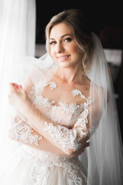 Beyaz elbiseli lüks gelin düğün törenine hazırlanırken poz veriyor.