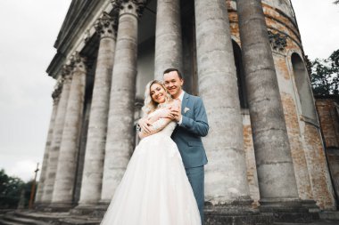 Doğadaki düğün çifti birbirine sarılıyor. Beyaz elbiseli güzel bir kız. Takım elbiseli adam