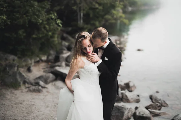 Glückliche und romantische Szene von frisch verheirateten jungen Hochzeitspaaren, die am schönen Strand posieren — Stockfoto