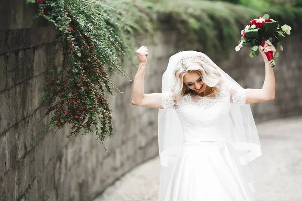 Schöne junge Luxusbraut im Brautkleid posiert im Park — Stockfoto