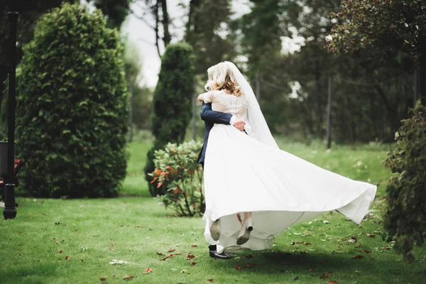 Newly married couple running and jumping in park while holding hands — Stock Photo, Image