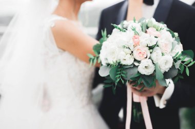 Çiçek buketi taşıyan mükemmel bir düğün çifti.