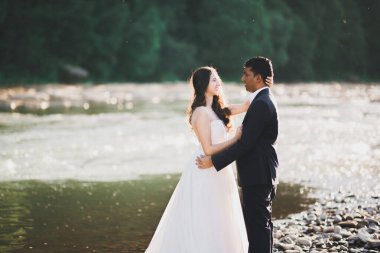 Doğadaki düğün çifti birbirine sarılıyor. Beyaz elbiseli güzel bir kız. Takım elbiseli adam