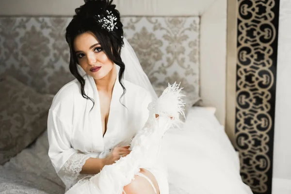 Splendida sposa in accappatoio in posa e preparazione per la cerimonia di nozze faccia in una stanza — Foto Stock