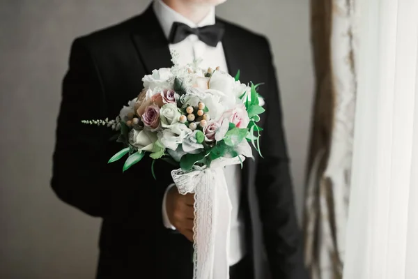 Hermoso hombre, novio celebración de ramo de boda grande y hermosa con flores — Foto de Stock