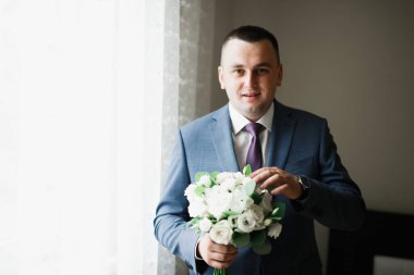 Güzel adam, damat elinde çiçeklerle büyük ve güzel bir düğün buketi tutuyor