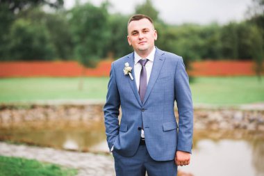 Yaka çiçeğiyle poz veren mutlu yakışıklı damat.