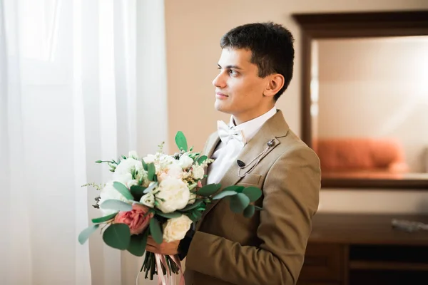 Hermoso hombre, novio celebración de ramo de boda grande y hermosa con flores — Foto de Stock