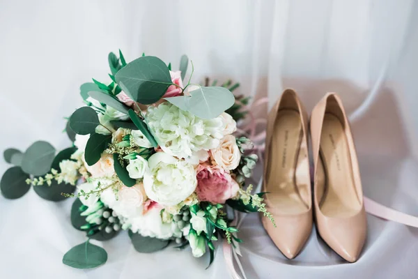 Ζεύγος κομψών και στυλάτων νυφικών παπουτσιών με μπουκέτο με τριαντάφυλλα και άλλα λουλούδια. — Φωτογραφία Αρχείου