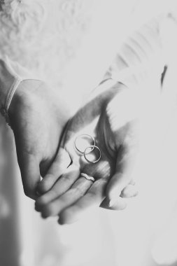 Zarif beyaz elbiseli güzel bir gelin elinde alyanslar tutuyor.