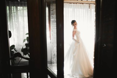 Cüppeli muhteşem gelin bir odada düğün töreni için poz veriyor ve hazırlanıyor.