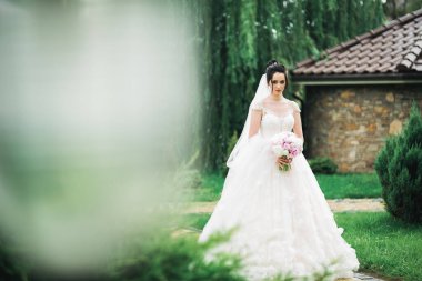 Parkta poz veren gelinlikli güzel, lüks bir gelin.