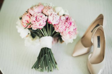 Bir çift zarif ve şık gelin ayakkabısı ile bir buket gül ve diğer çiçeklerle.