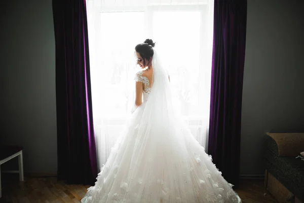 Linda noiva em roupão posando e se preparando para o rosto cerimônia de casamento em uma sala — Fotografia de Stock