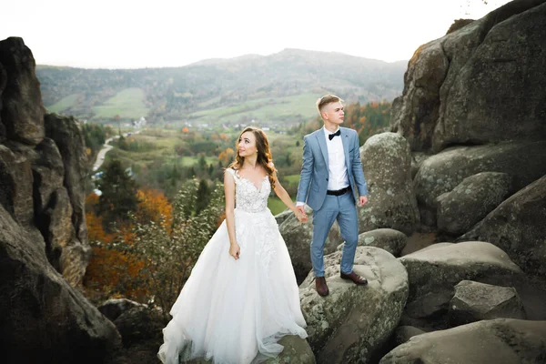 Gyönyörű gyönyörű menyasszony pózol vőlegény és szórakozás közelében hegyek csodálatos kilátás, hely a szöveg, esküvői pár — Stock Fotó