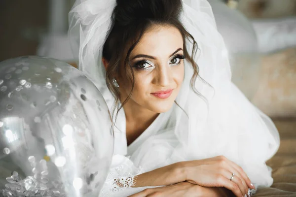 Hermosa novia con vestido de novia de moda con plumas con maquillaje de lujo deleite y peinado, estudio sesión de fotos interior — Foto de Stock