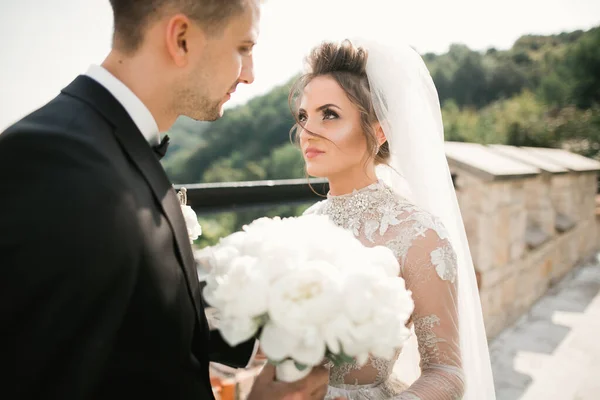 Vackra unga bröllop par poserar med bukett blommor i händerna — Stockfoto