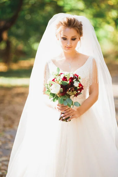 Розкішна весільна наречена, дівчина позує і посміхається з букетом — стокове фото