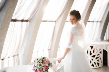 Gelin çiçekli büyük ve güzel bir düğün buketi tutuyor.