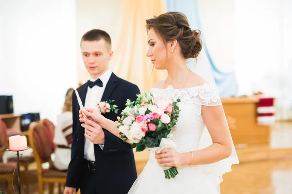 Brud- och brudgum som håller ljus i kyrkan — Stockfoto