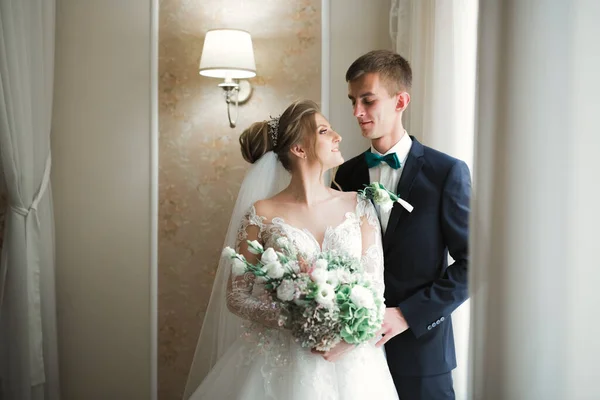 Beau jeune couple de mariage posant avec bouquet de fleurs dans les mains — Photo