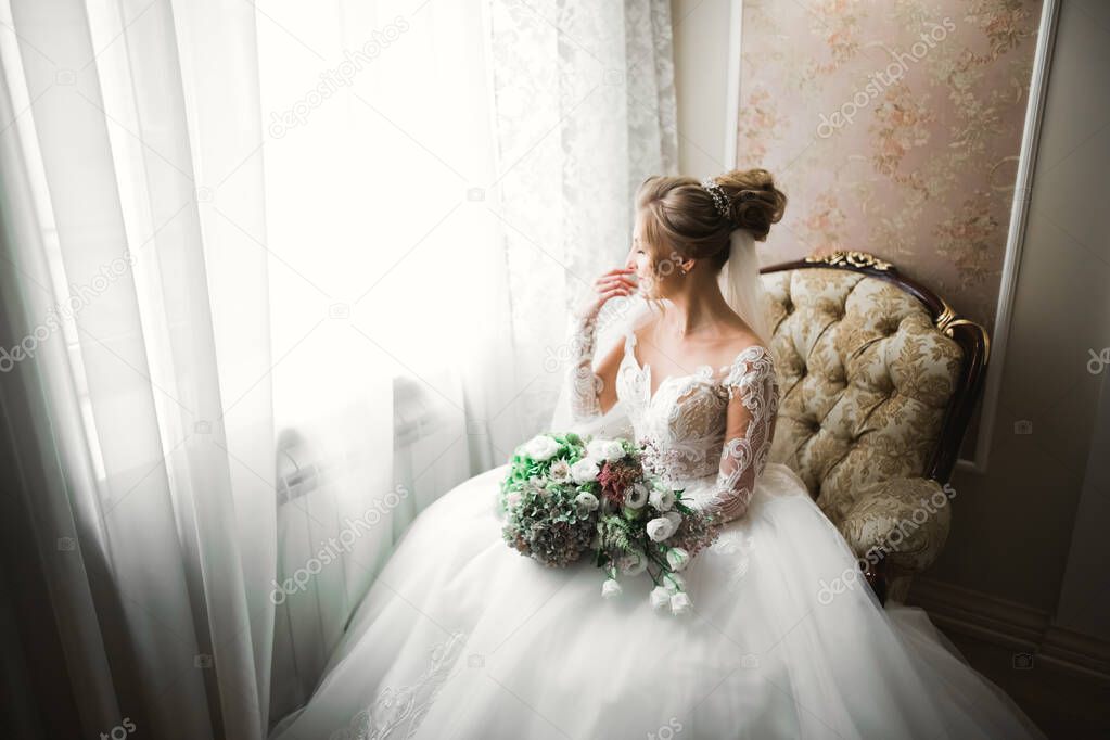 Luxury bride in white dress posing while preparing for the wedding ceremony