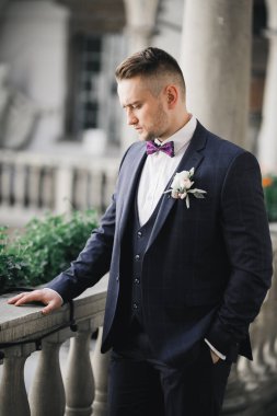 Yaka çiçeğiyle poz veren mutlu yakışıklı damat.