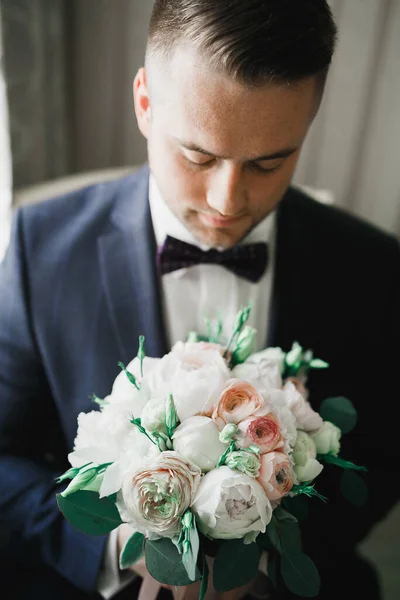 Homem bonito, noivo segurando grande e bonito buquê de casamento com flores — Fotografia de Stock
