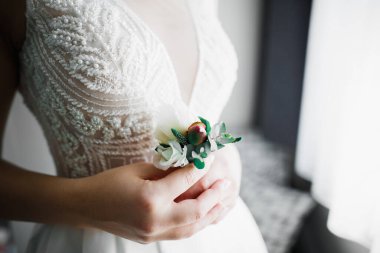 Zarif beyaz elbiseli güzel gelin elinde bir buket çiçek tutuyor.