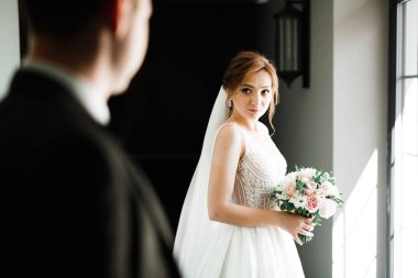 Çekici gelinin portresi, uzun saçlı, büyük buketli poz veren.