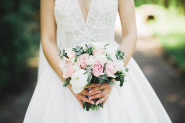 Gelin çiçekli büyük ve güzel bir düğün buketi tutuyor.