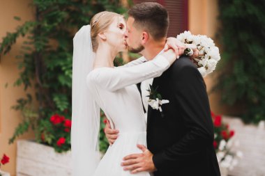Güzel gelin ve damat düğün günlerinde kucaklaşıp öpüşürler.