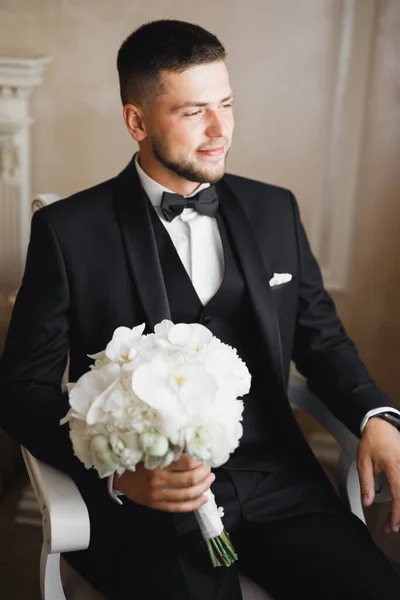 Beautiful man, groom holding big and beautiful wedding bouquet with flowers