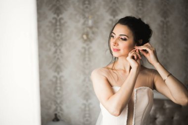 Cüppeli muhteşem gelin bir odada düğün töreni için poz veriyor ve hazırlanıyor.