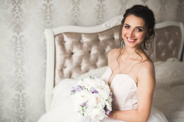 Cüppeli muhteşem gelin bir odada düğün töreni için poz veriyor ve hazırlanıyor.