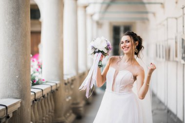 Gelin çiçekli büyük ve güzel bir düğün buketi tutuyor.