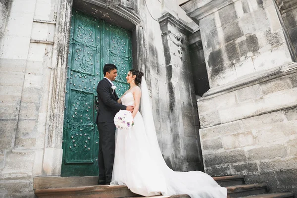 Preciosa pareja feliz de pie cerca el uno del otro y mirando a los ojos en el fondo de la ciudad vieja, foto de la boda, ciudad europea, día de la boda en Lviv —  Fotos de Stock
