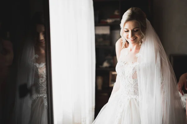 Hermosa novia con vestido de novia de moda con plumas con maquillaje de lujo deleite y peinado, estudio sesión de fotos interior —  Fotos de Stock