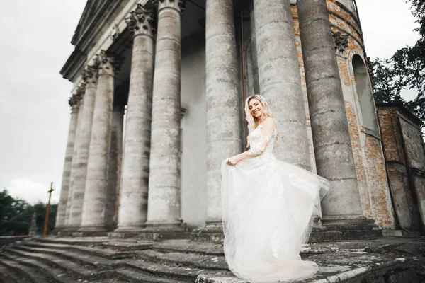 美しい花嫁は歴史的な建物の近くに完璧なドレスで回転 — ストック写真