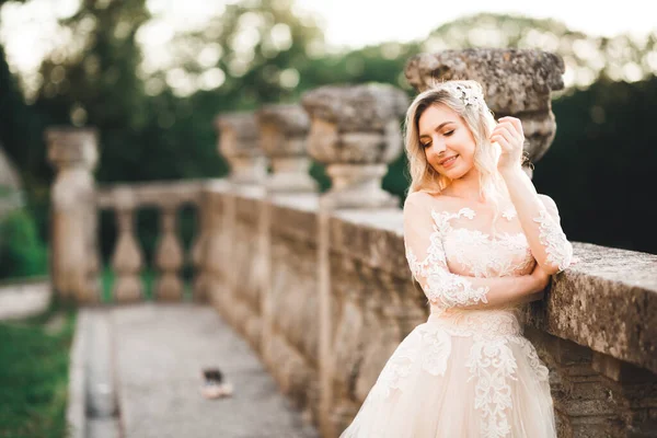 Belle mariée brune dans une élégante robe blanche tenant bouquet posant près du château — Photo