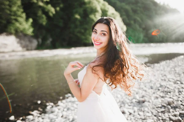 Porträt einer atemberaubenden Braut mit langen Haaren, die am Fluss steht — Stockfoto